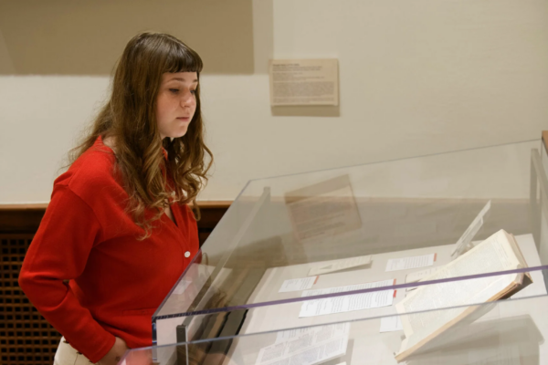 Jane Frieman looking into glass display case filled with exhibit items.