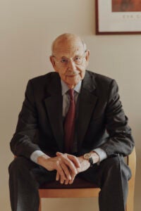 Portrait of Stephen Breyer leaning forward as he sits on a chair in his office at Harvard Law School