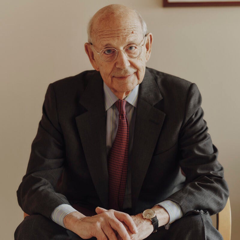Portrait of Stephen Breyer leaning forward as he sits on a chair in his office at Harvard Law School
