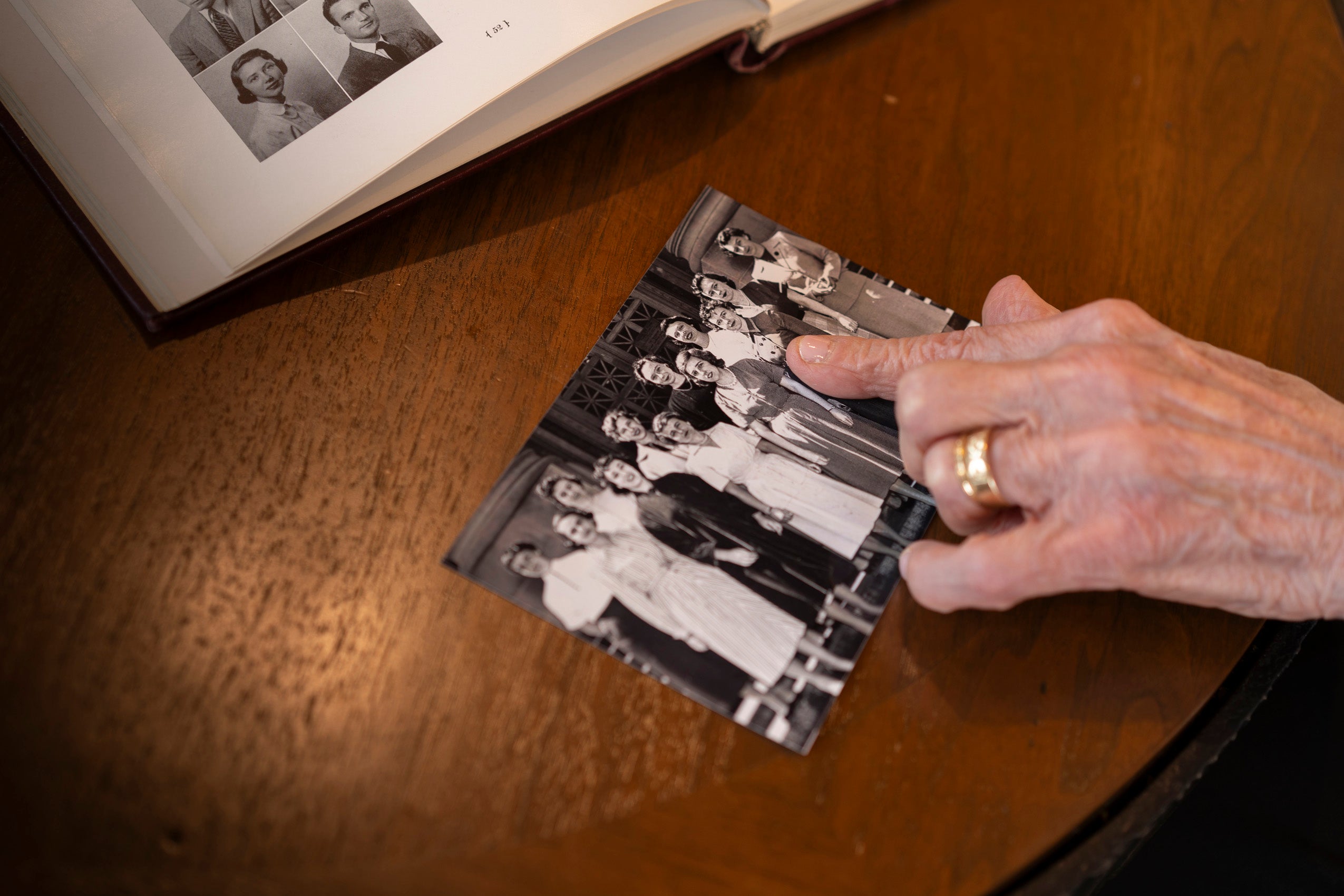 A close up of someone pointing to a woman pictured in an archival photo of a group of women posing on the steps of a building