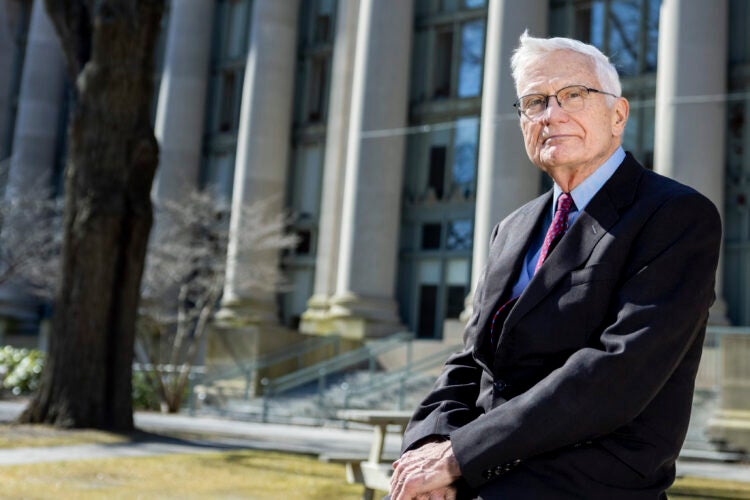 Portrait of man leaning on a table in the front of a large building with columns