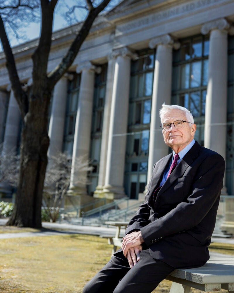 Portrait of man leaning on a table in the front of a large building with columns