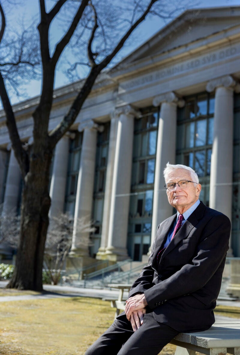 Portrait of man leaning on a table in the front of a large building with columns