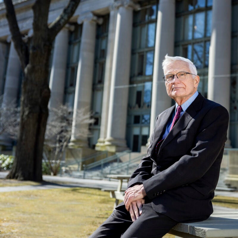 Portrait of man leaning on a table in the front of a large building with columns