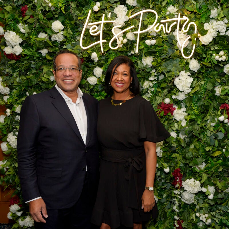 HLS alumni pose in front of a wall of flowers