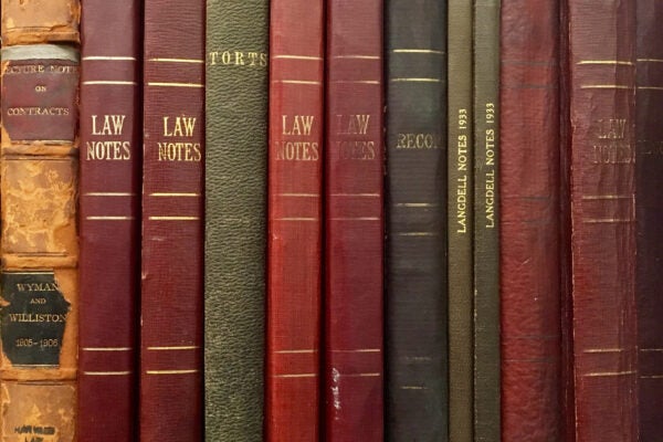 The spines of 12 volumes of class notes in different colors and sizes, lined up together.