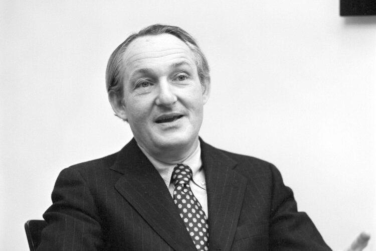 A man sitting in a chair talking with someone.