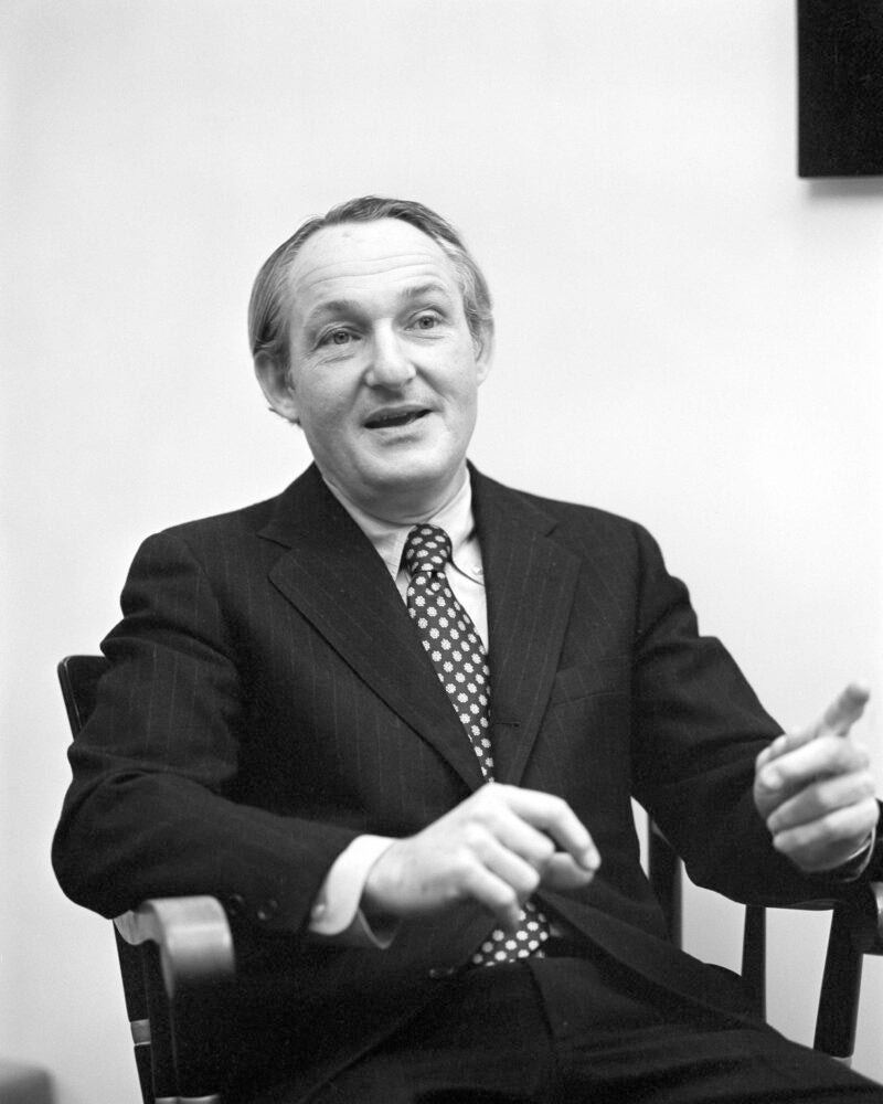 A man sitting in a chair talking with someone.