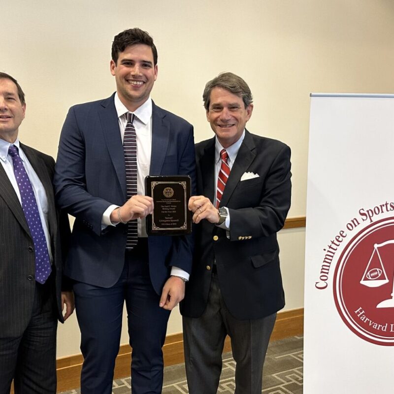 three men smile as one holds his award