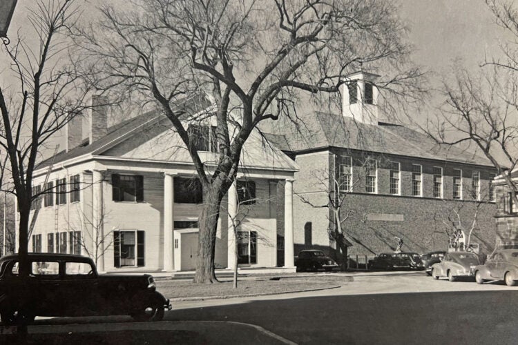 A white building with columns next to a brick building.