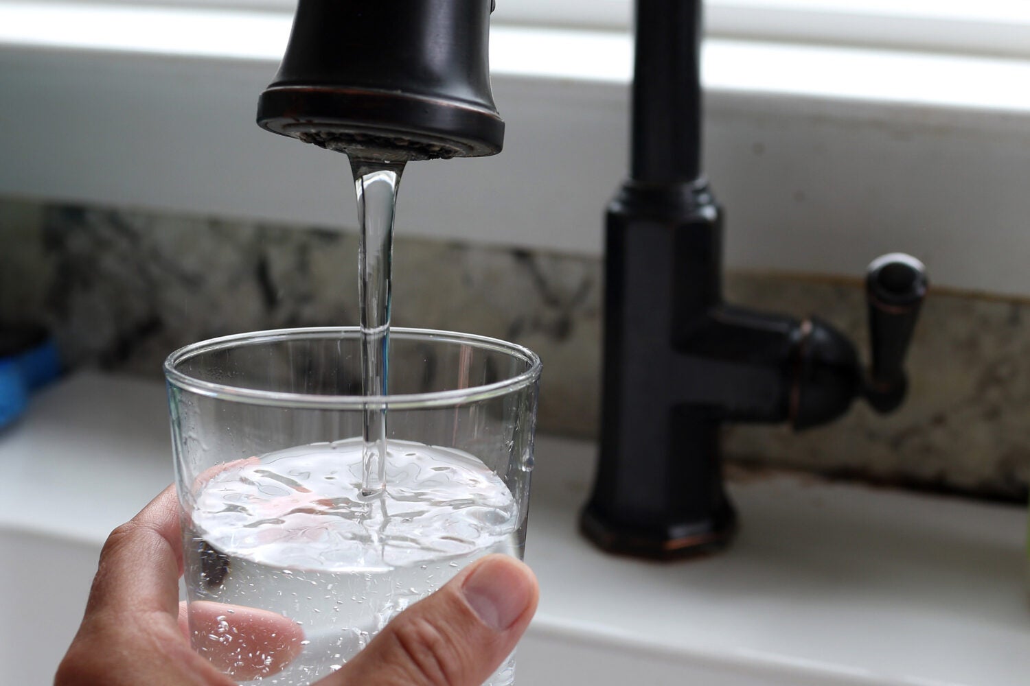 Glass of water under a running faucet.