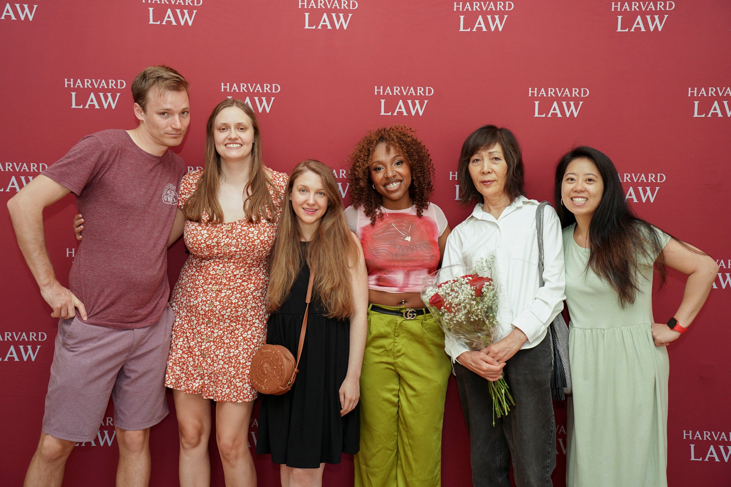A group of students having their photo taken in front of a step and repeat