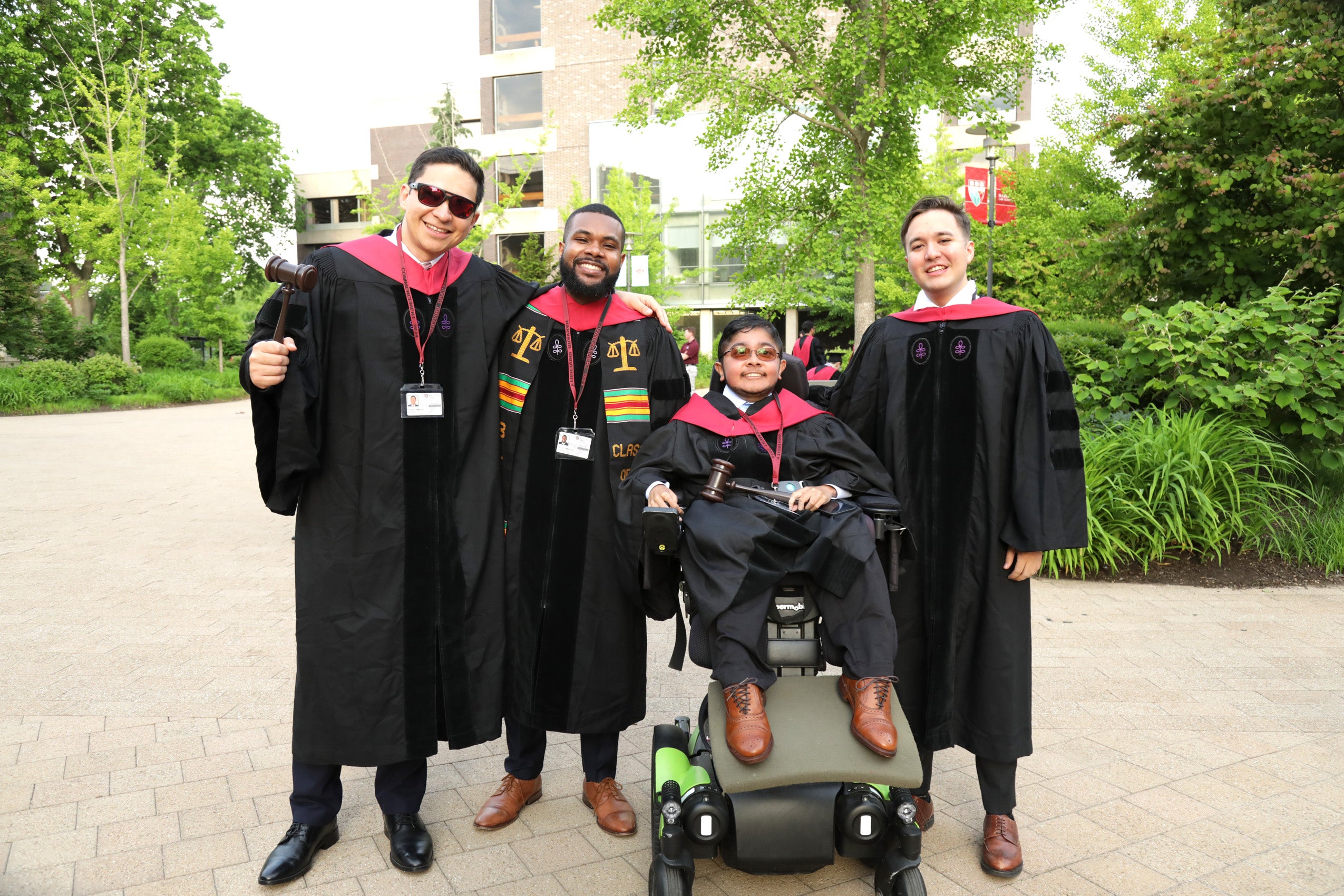 Four students gathered wearing Commencement regalia
