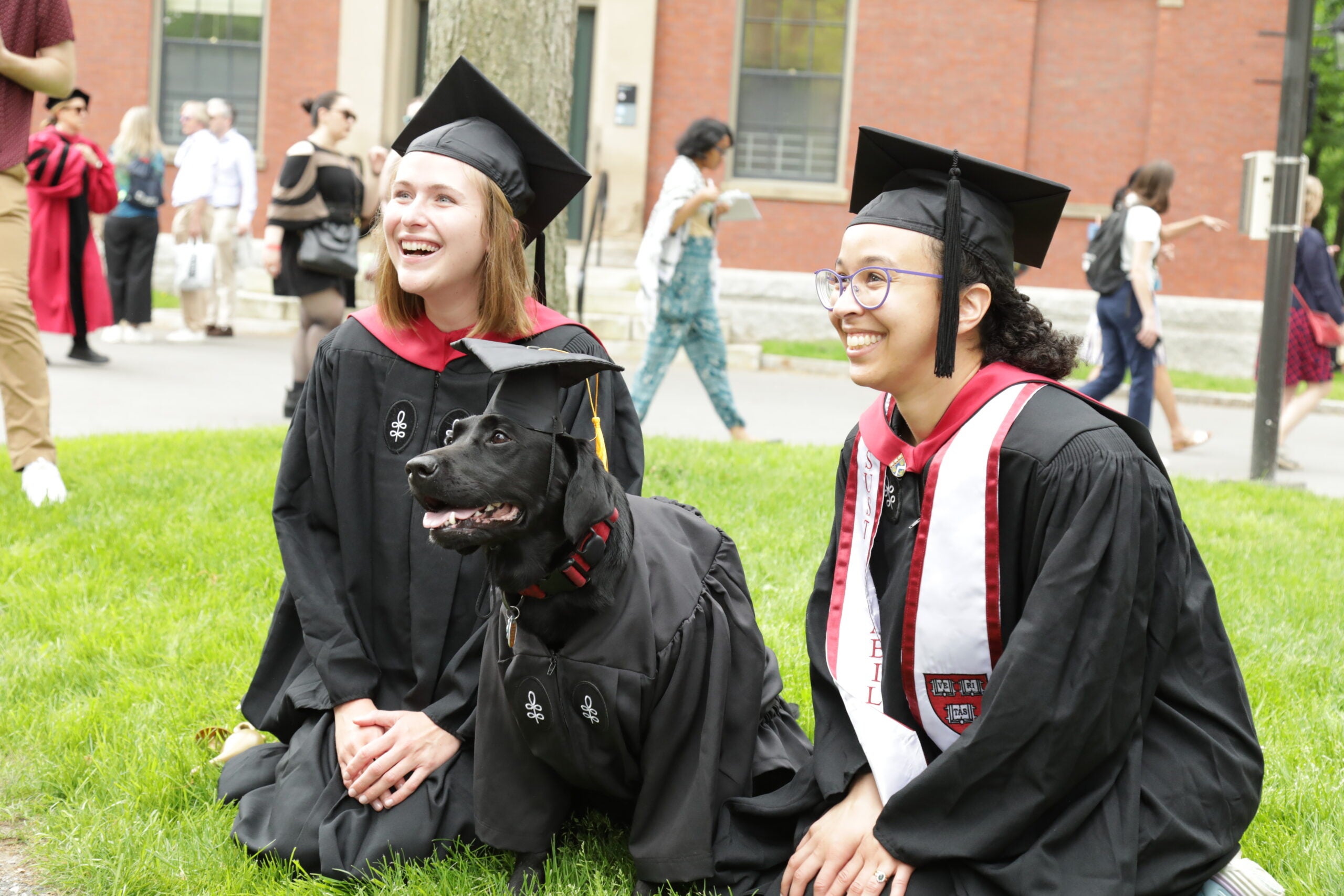Two graduates posing with a dog in regalia