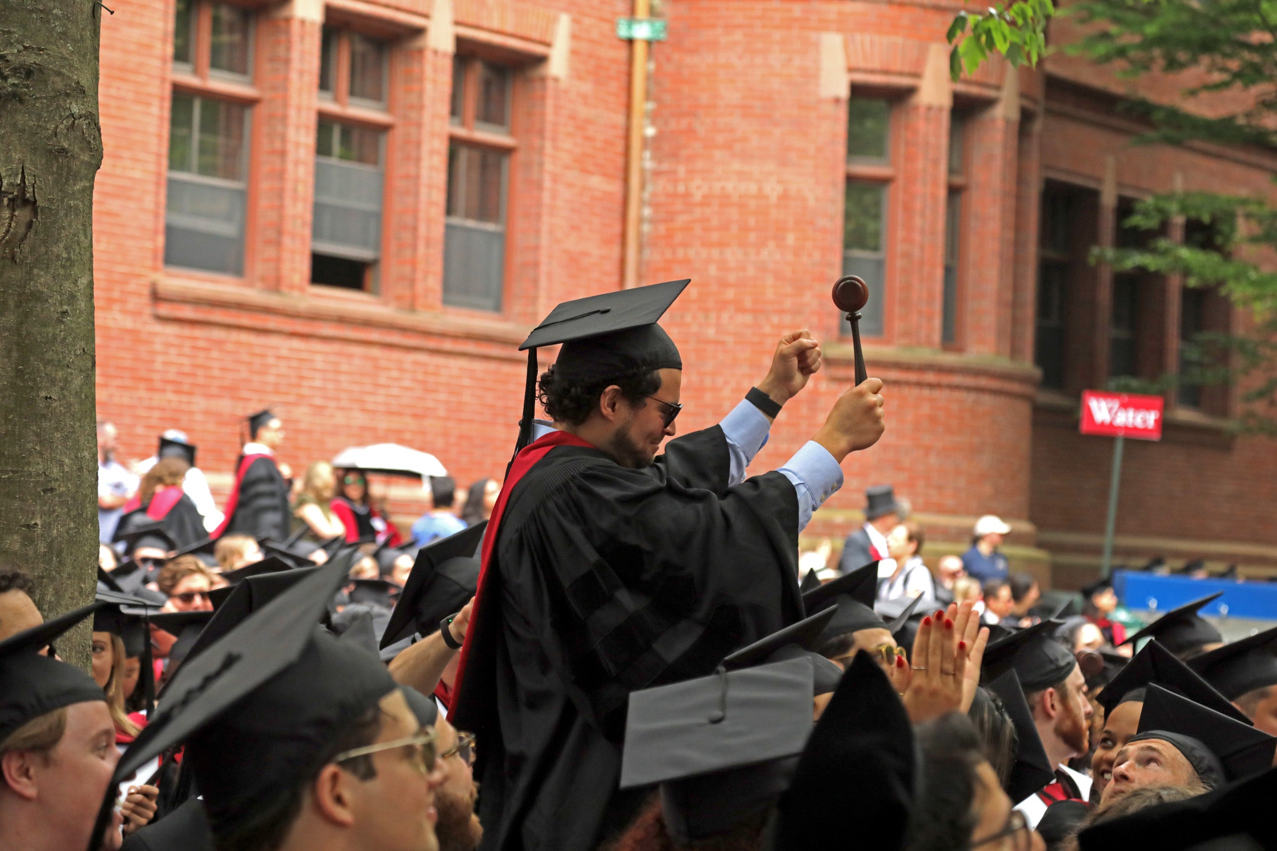 A graduate standing up and cheering with his gavel