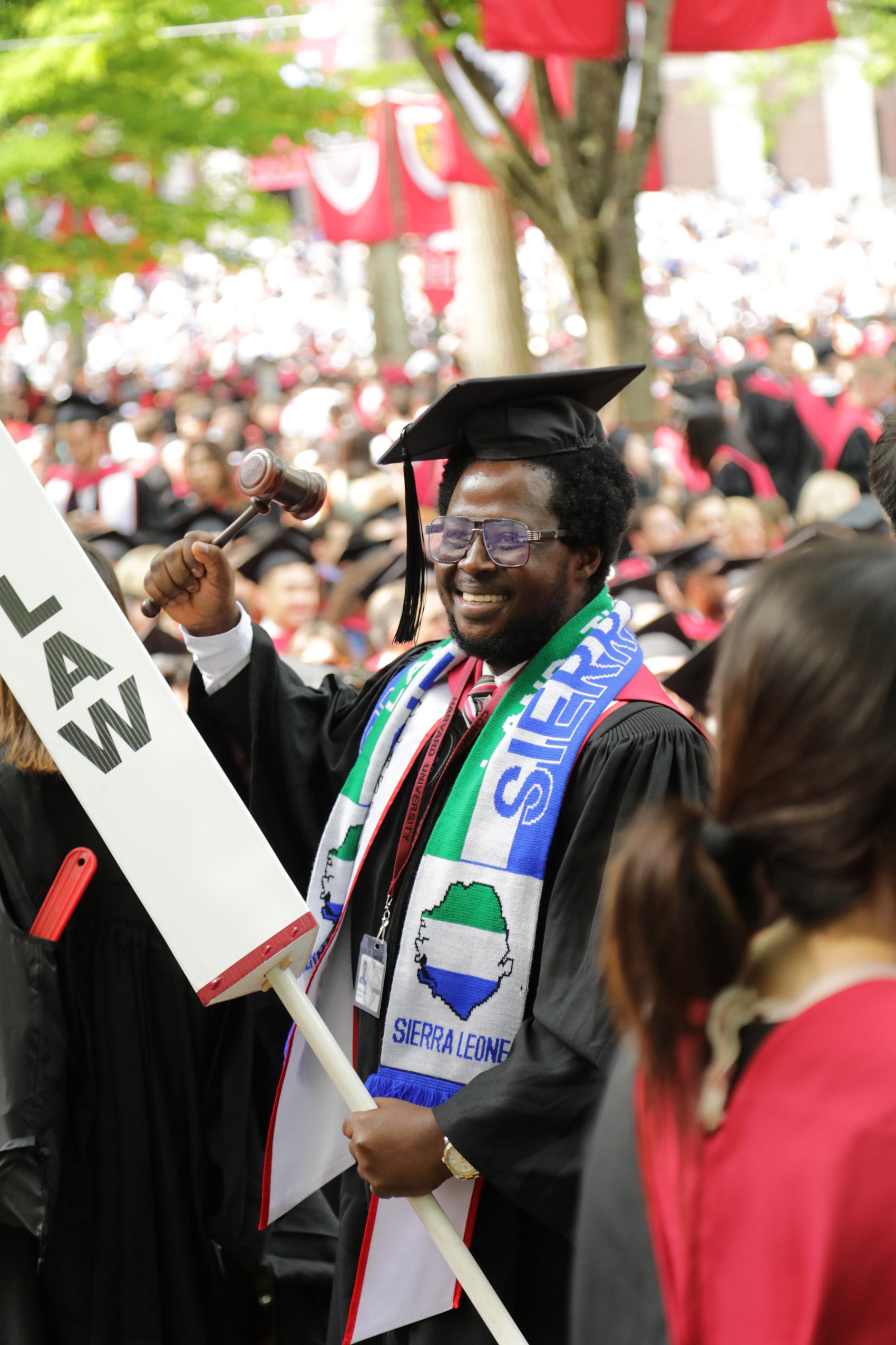 A graduating student holding his gavel and a LAW pillar