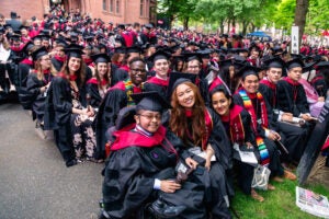 Graduating students seated in Harvard Yard, smiling