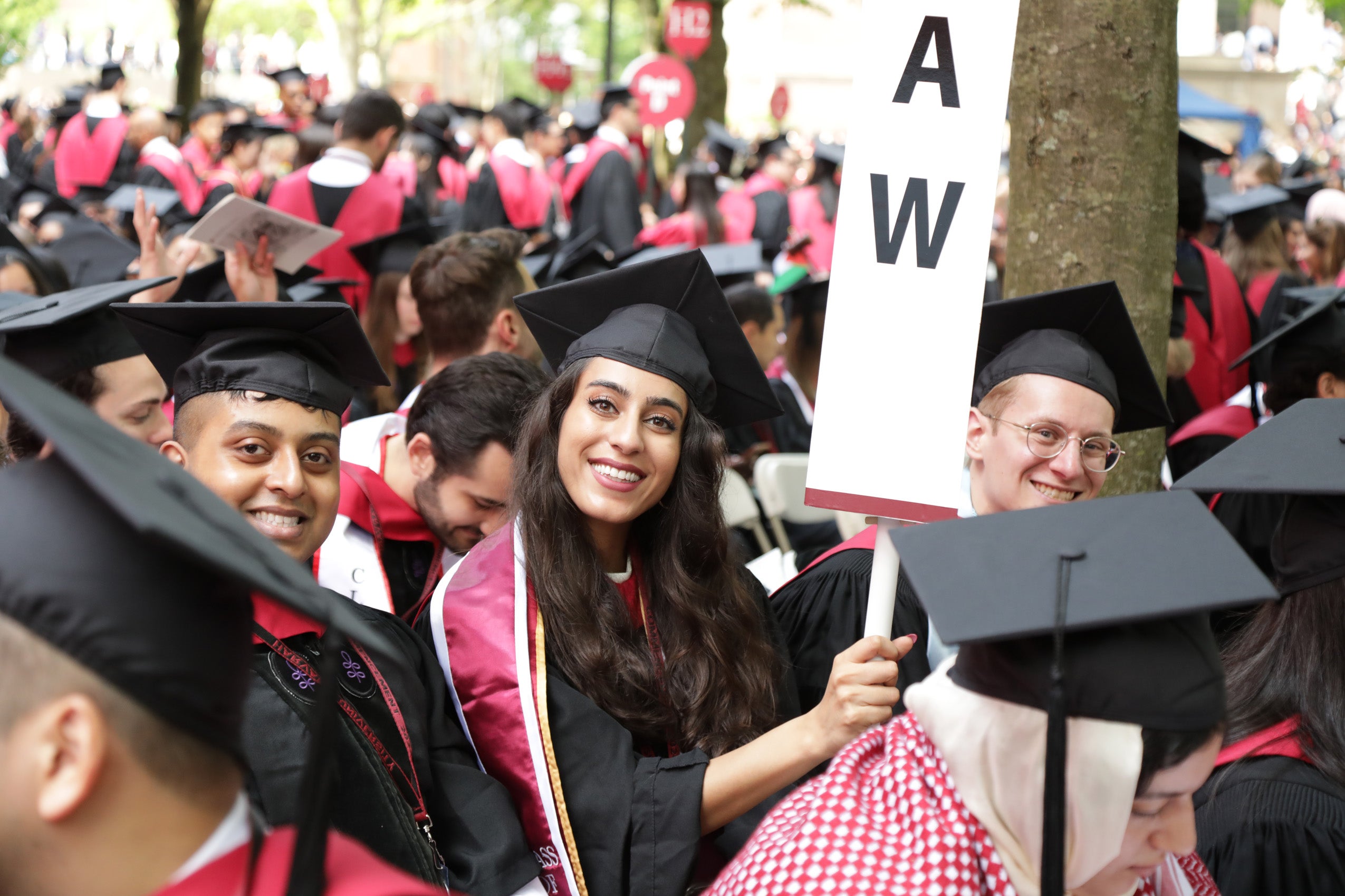Three smiling graduating students, one holding a LAW pillar
