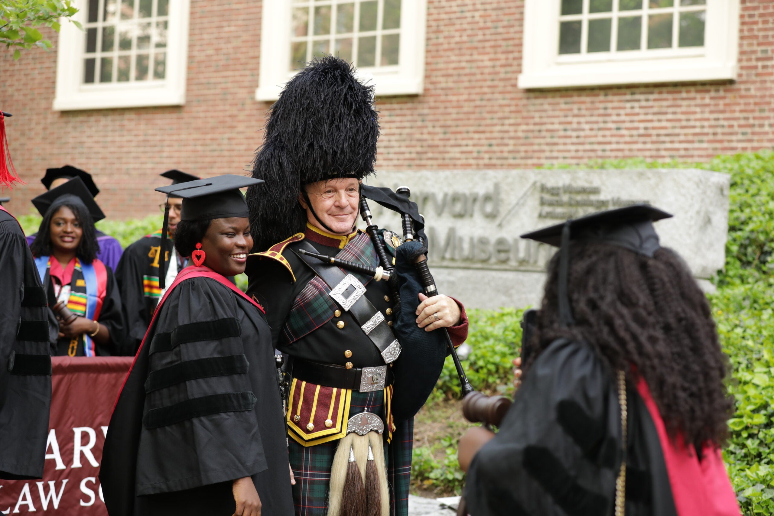 A graduating student posing for a photo with a bagpipe player
