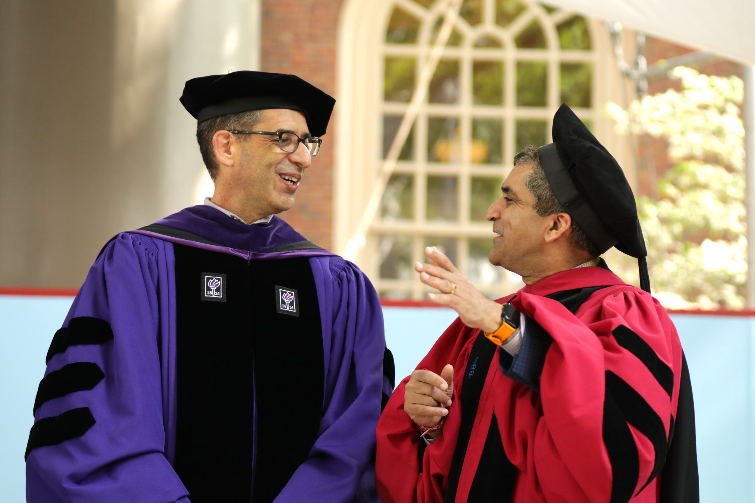 Two faculty members in regalia having a conversation
