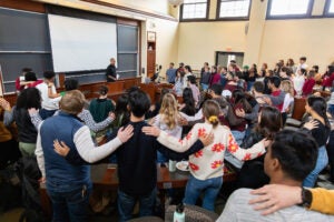 Full classroom of students with hands on shoulders of other students