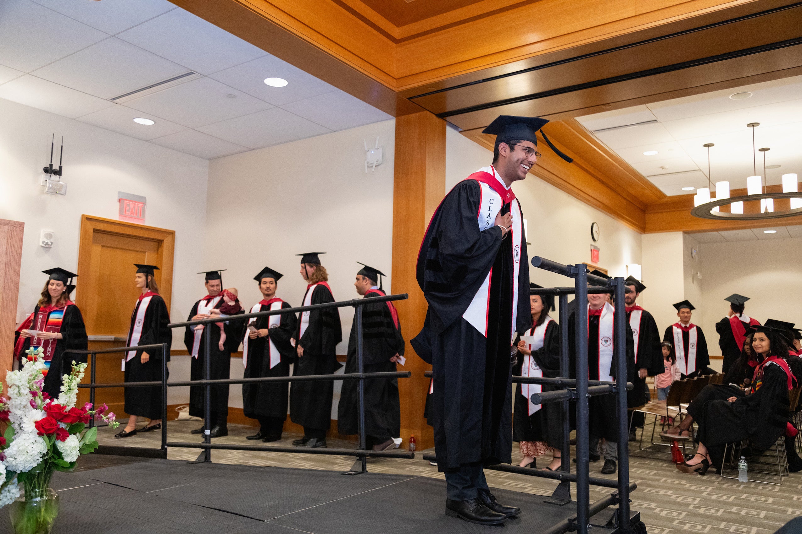 A man in cap and gown at a commencement ceremony looks out to the crowd during commencement ceremonies.