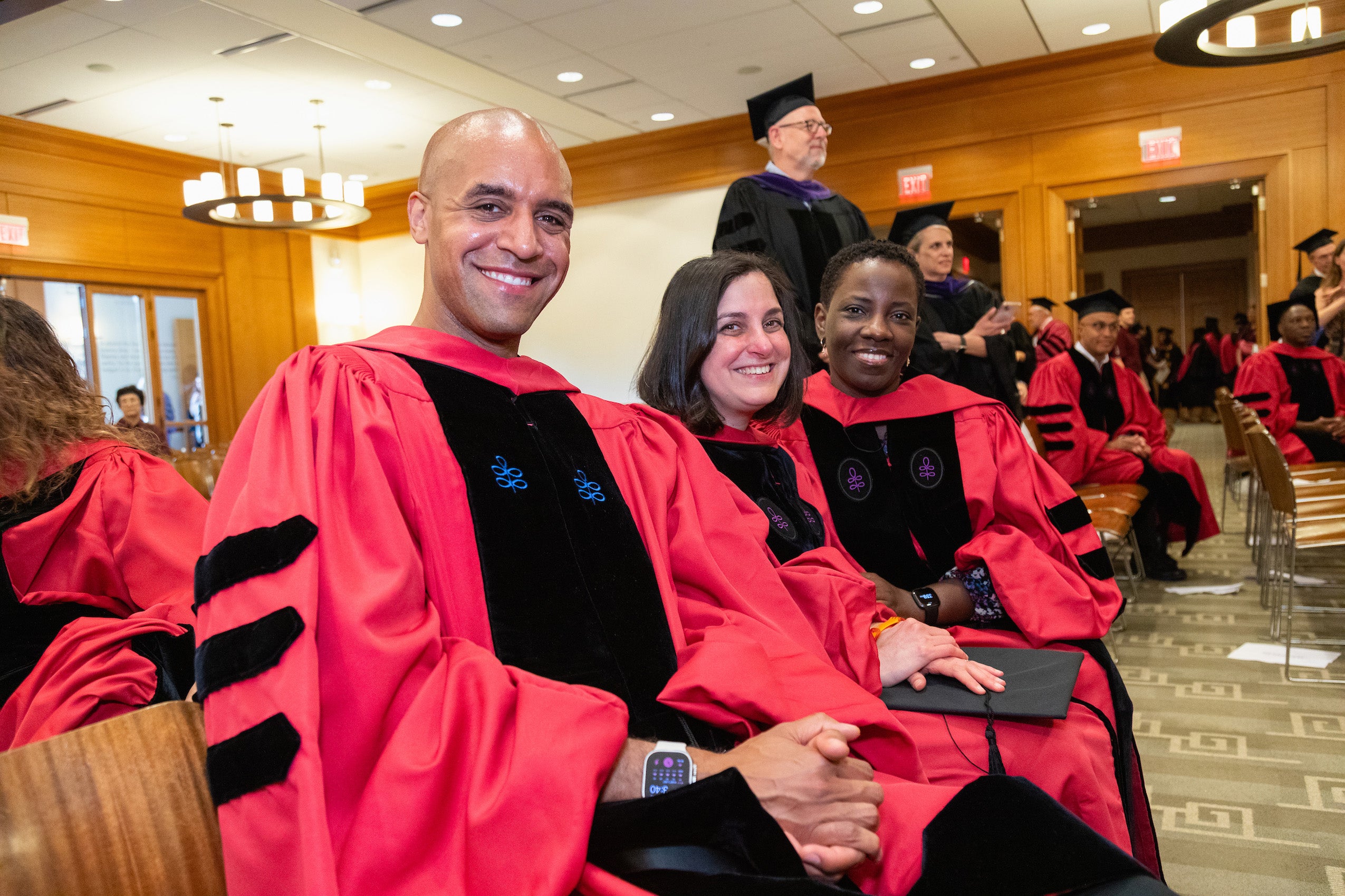 A group of faculty wearing cap and gown pose from their seats during Commencement ceremonies