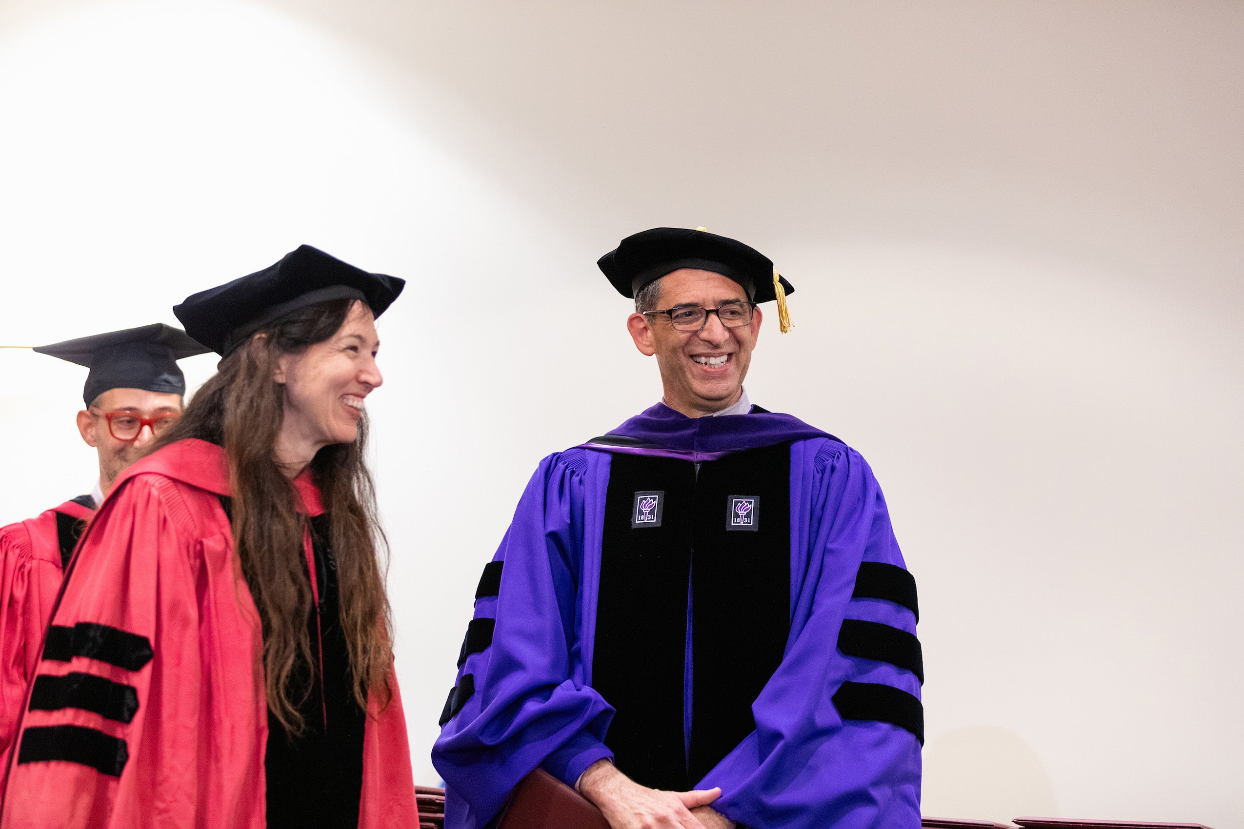 Dean Goldberg and Professor Gabriella Blum in cap and gown share a light moment