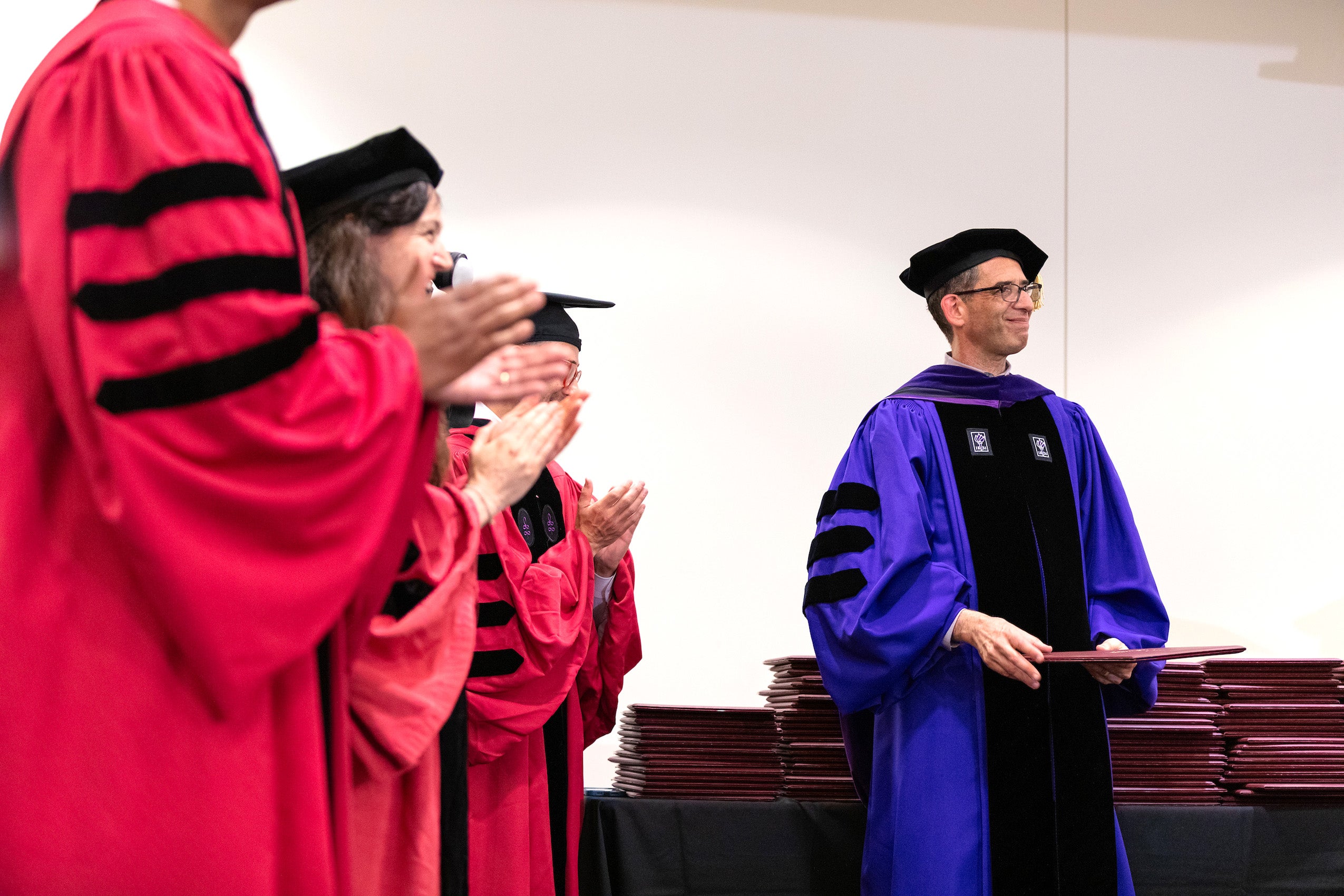 Dean Goldberg holds a diploma as he waits for the next student to come forward to receive a diploma