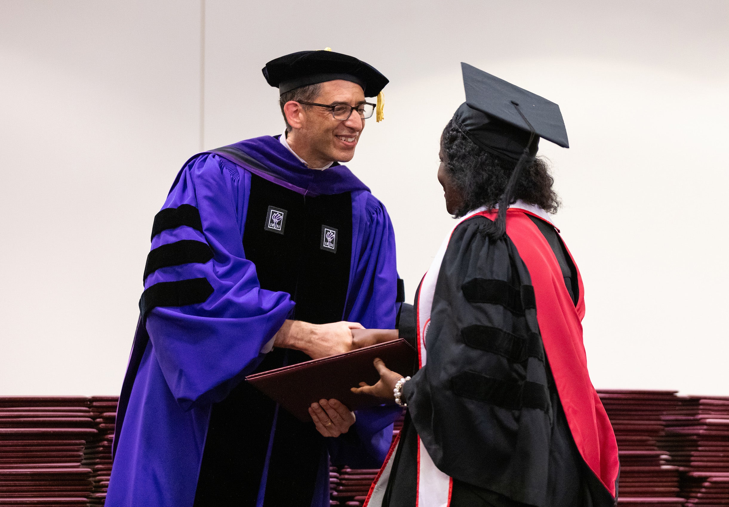 Dean Goldberg shakes the hand of a graduates and hands her he diploma