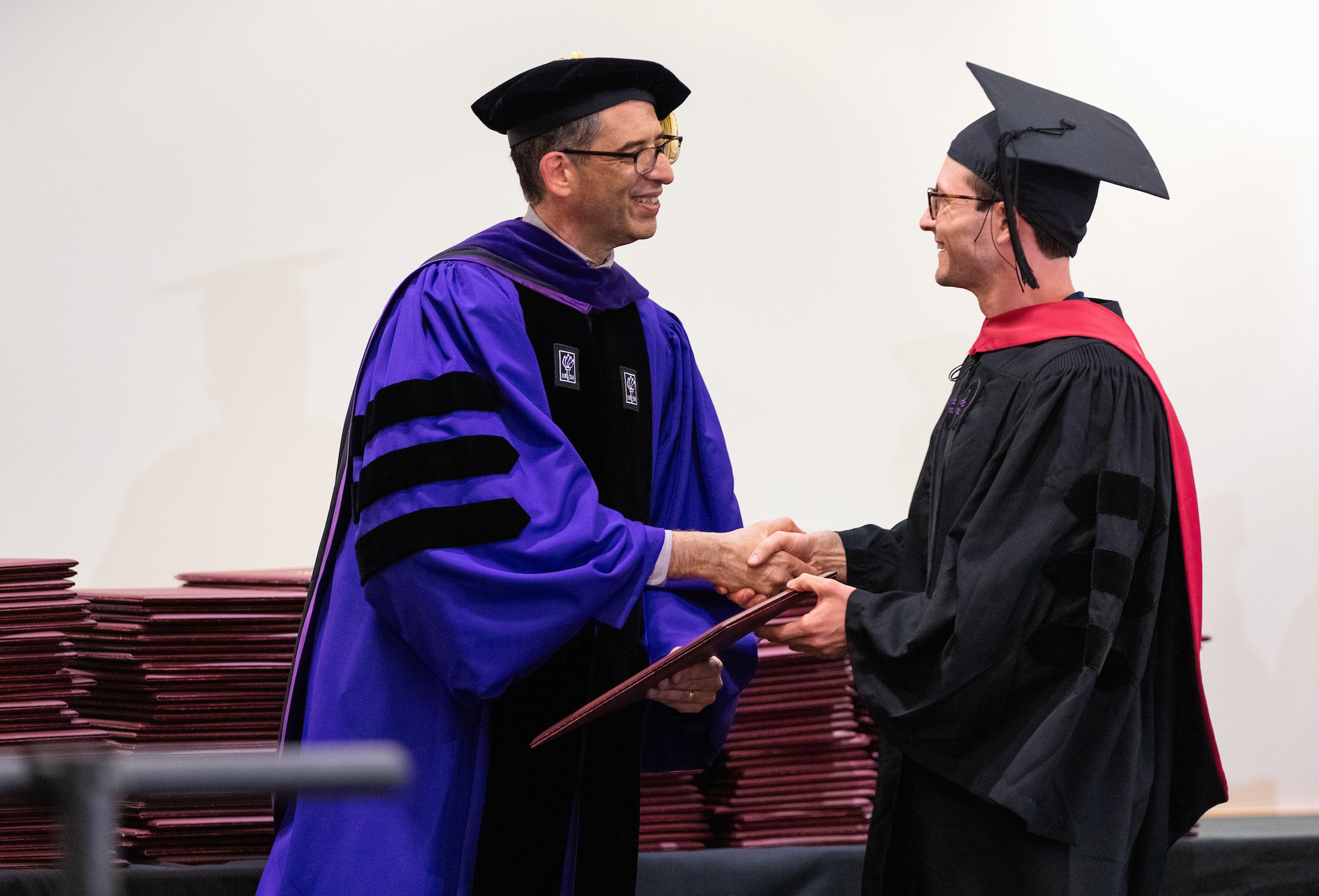 Dean Goldberg shakes the hand of a graduate and gives him his diploma