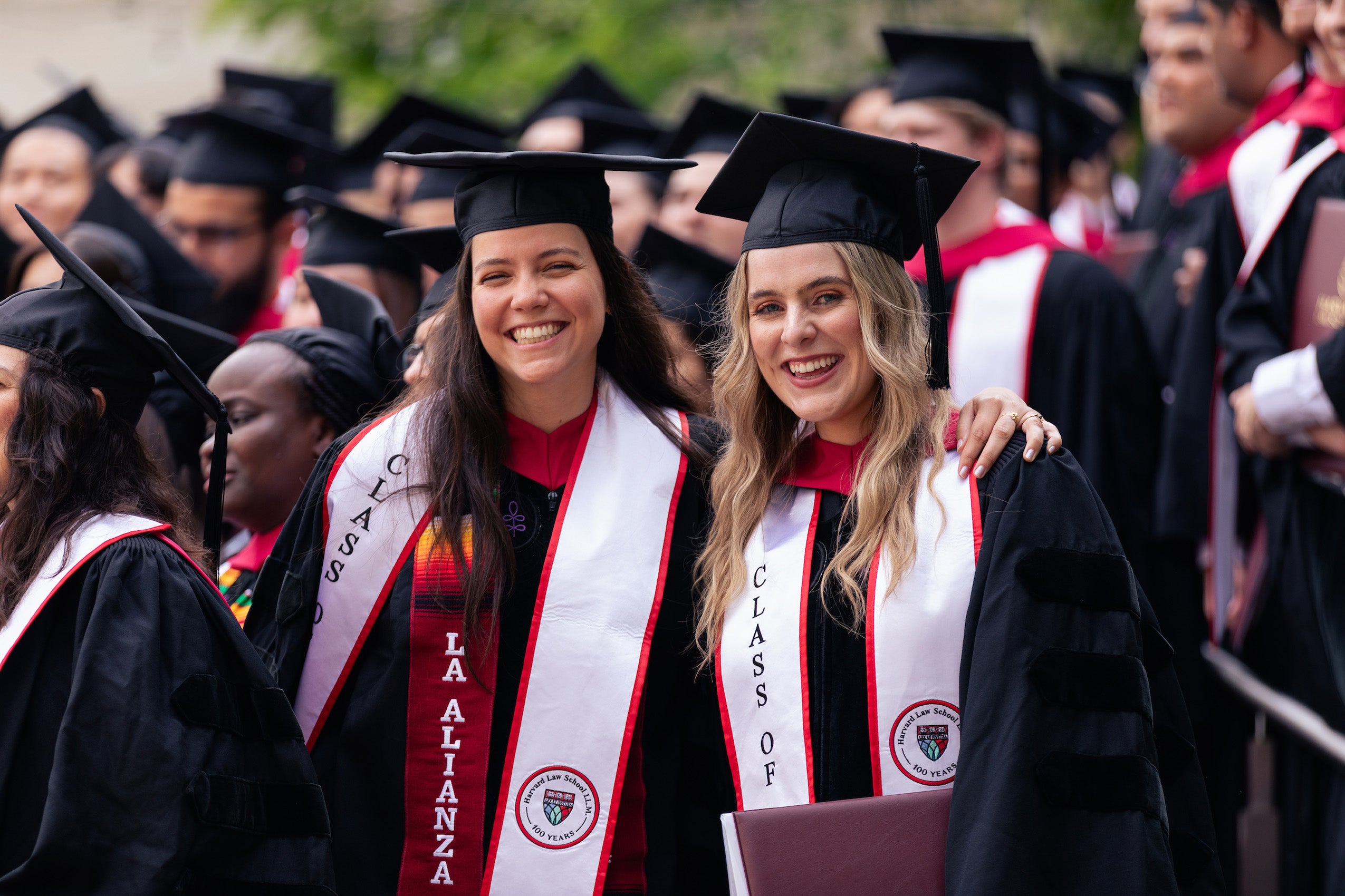 Two women in caps and gowns pose for a photo