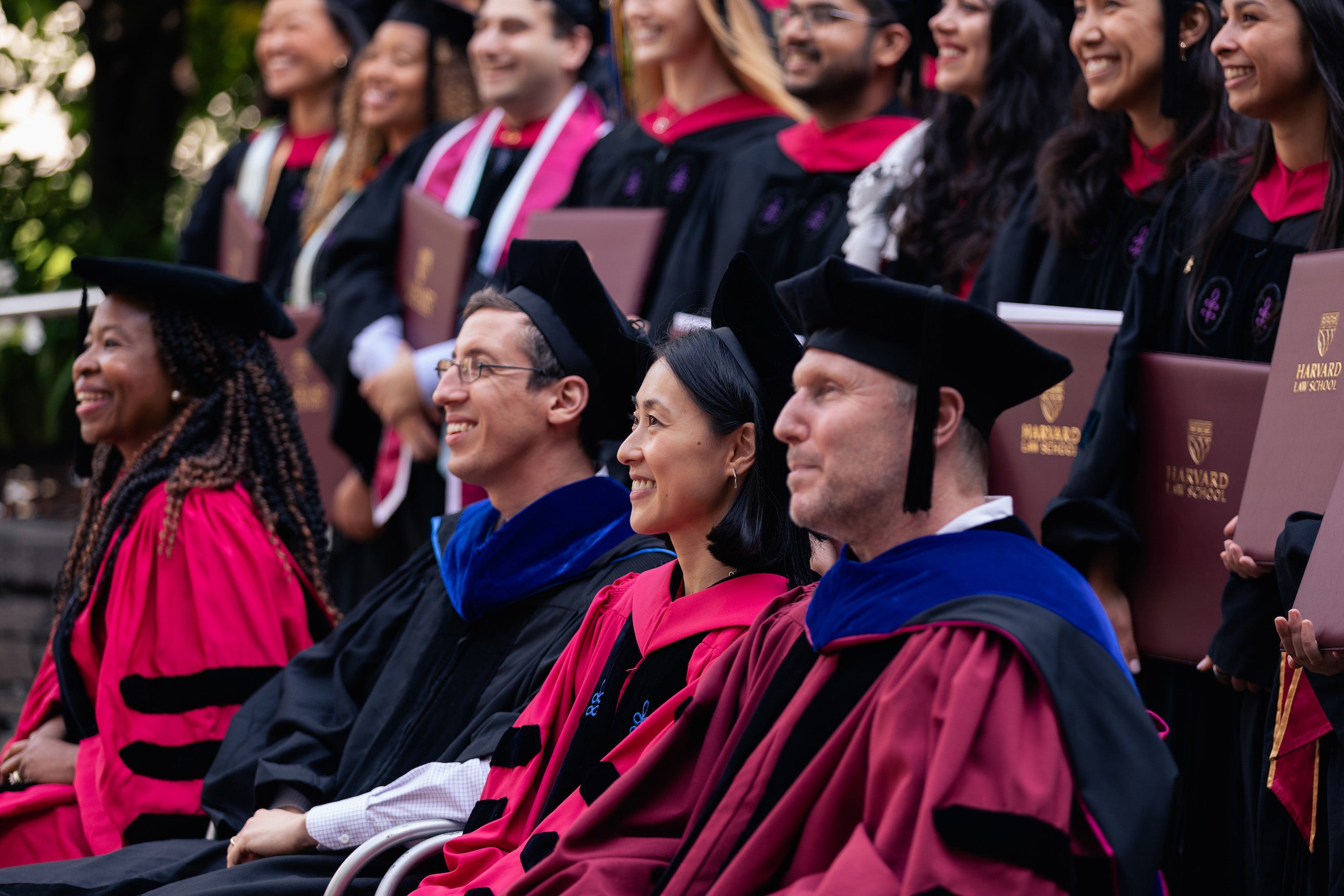 A close up of a row of faculty in cap and gown in a large group photo