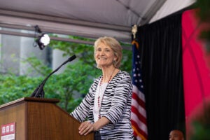 Christine Desan standing at a podium smiling