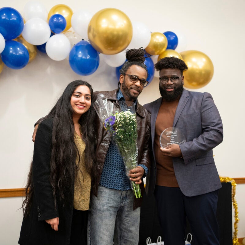 Three people post for the camera after an award is given.