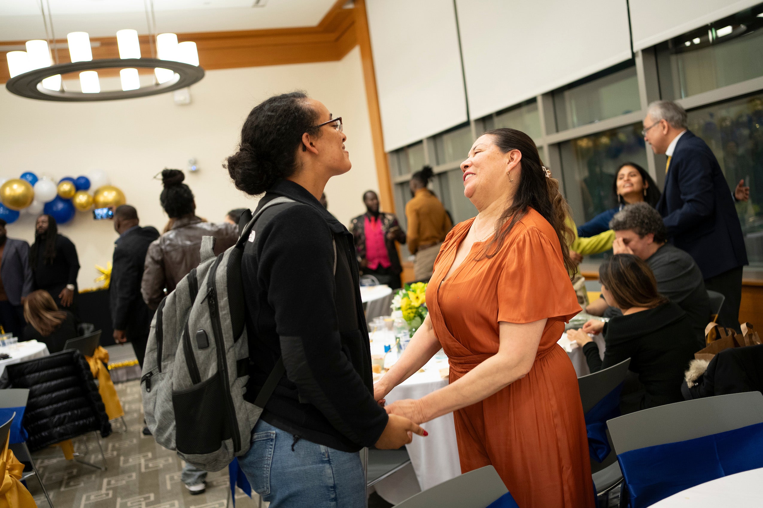 Two people at an event greet each other.