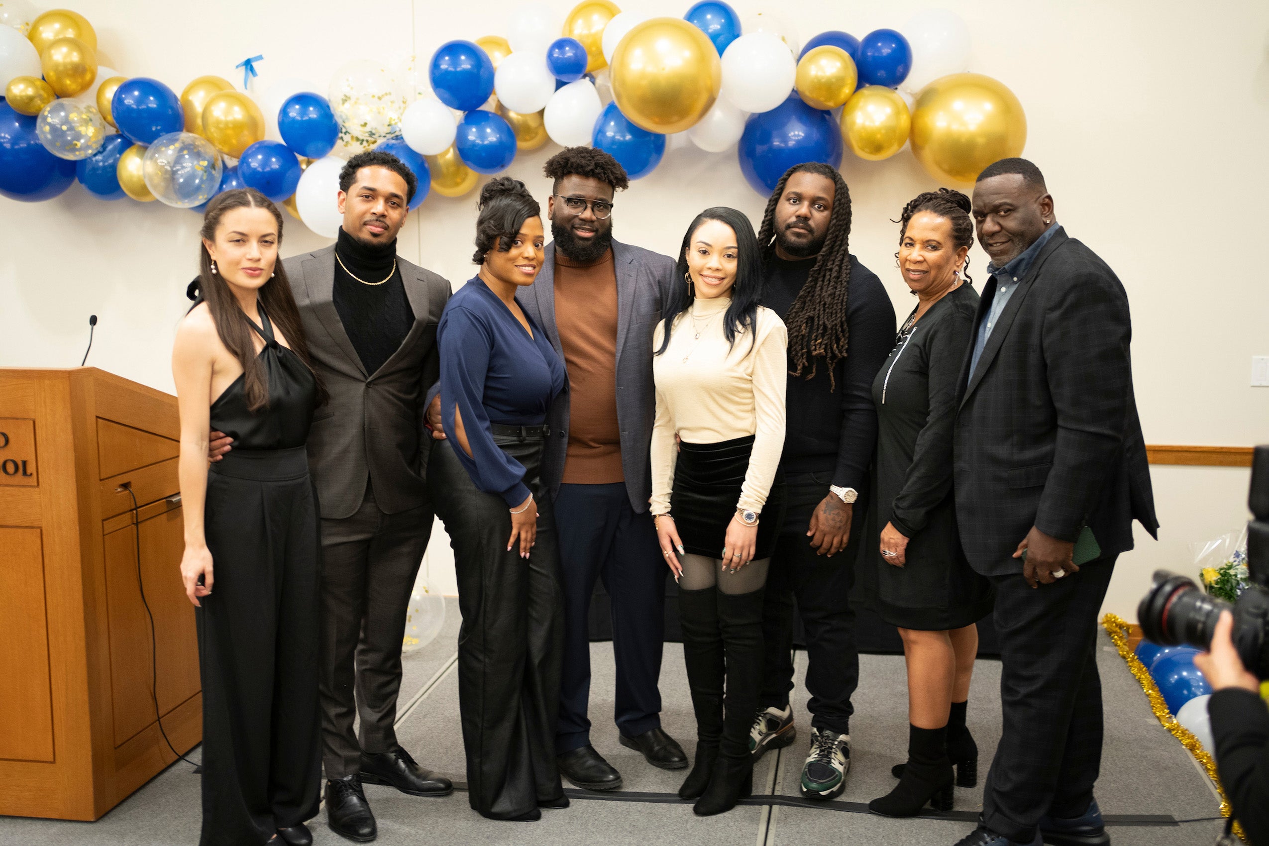 Eight people standing for a portrait at an event