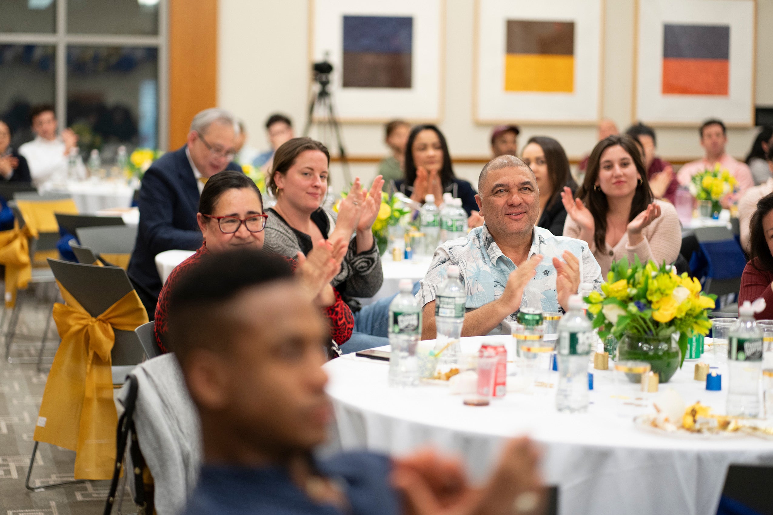 People sitting at a table at an event clapping.