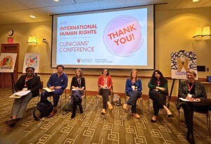 people sit in a row of chairs at the front of a conference room