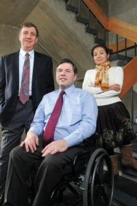 Three people, including a man in a wheelchair, pose