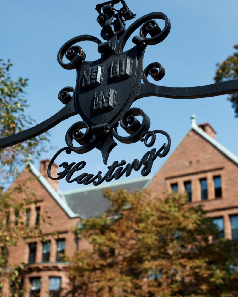 The black iron sign Hastings below the Harvard veritas with Hastings in the background.