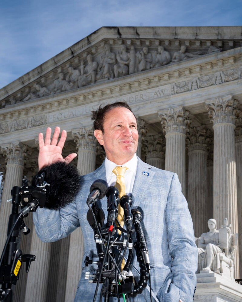 Jeff Landry speaking into microphones in front of the Supreme Court