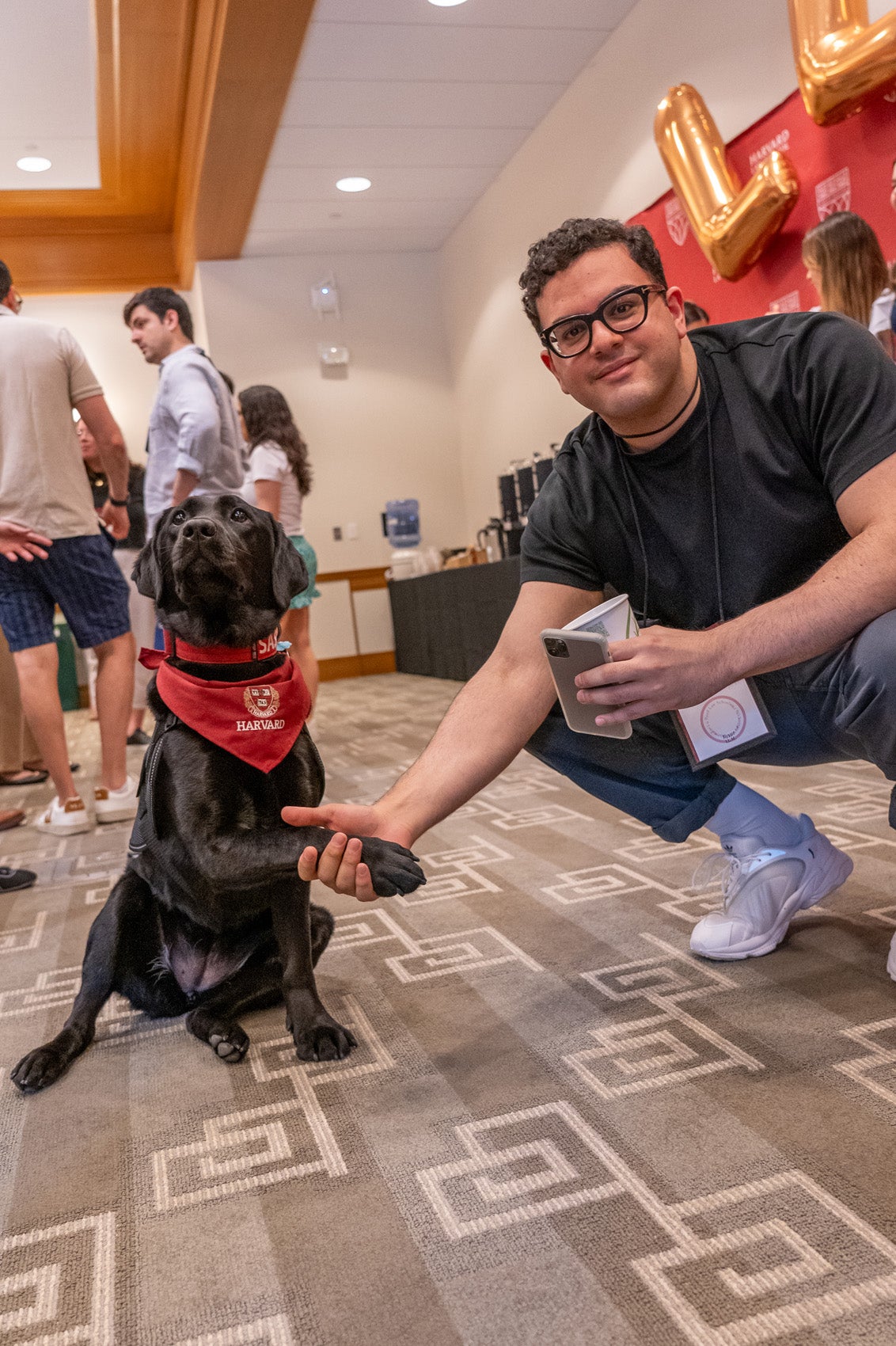 A student poses with Sasha, the Harvard Community Engagement Dog, during an LLM orientation session