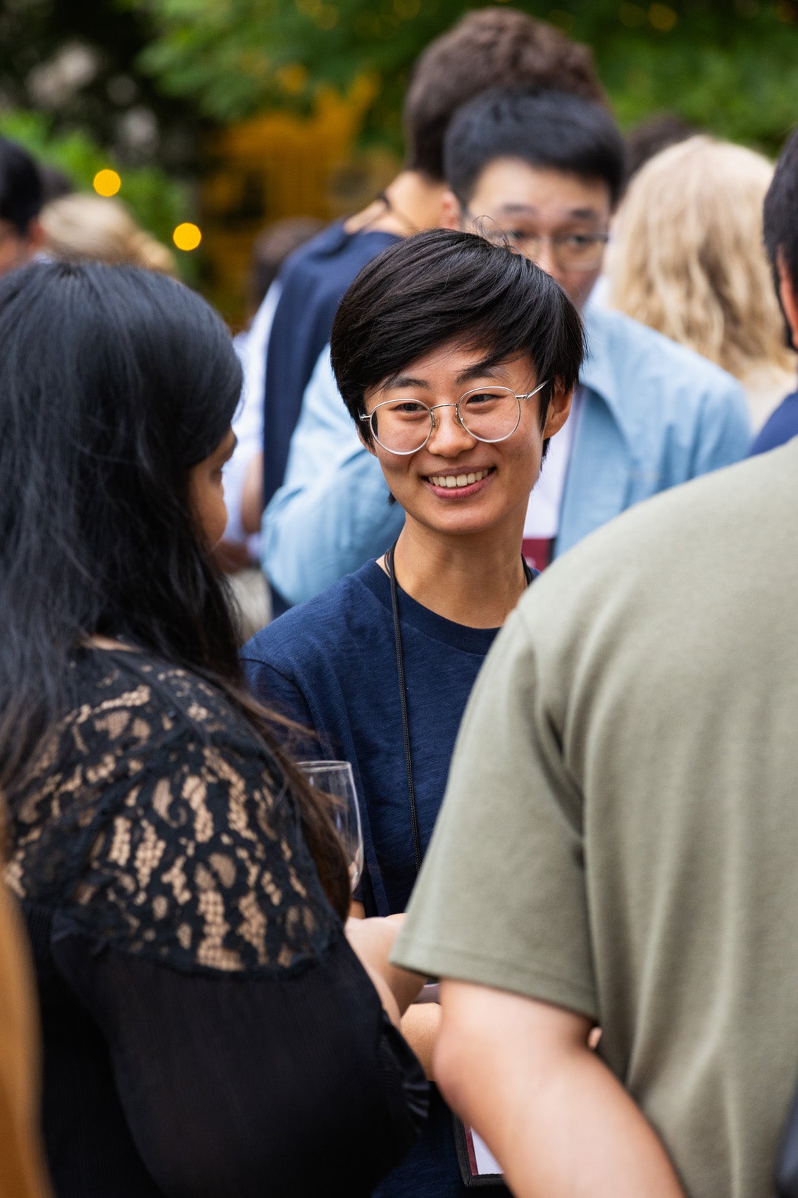 A close up of a woman smiling in a crowd of people at a reception.