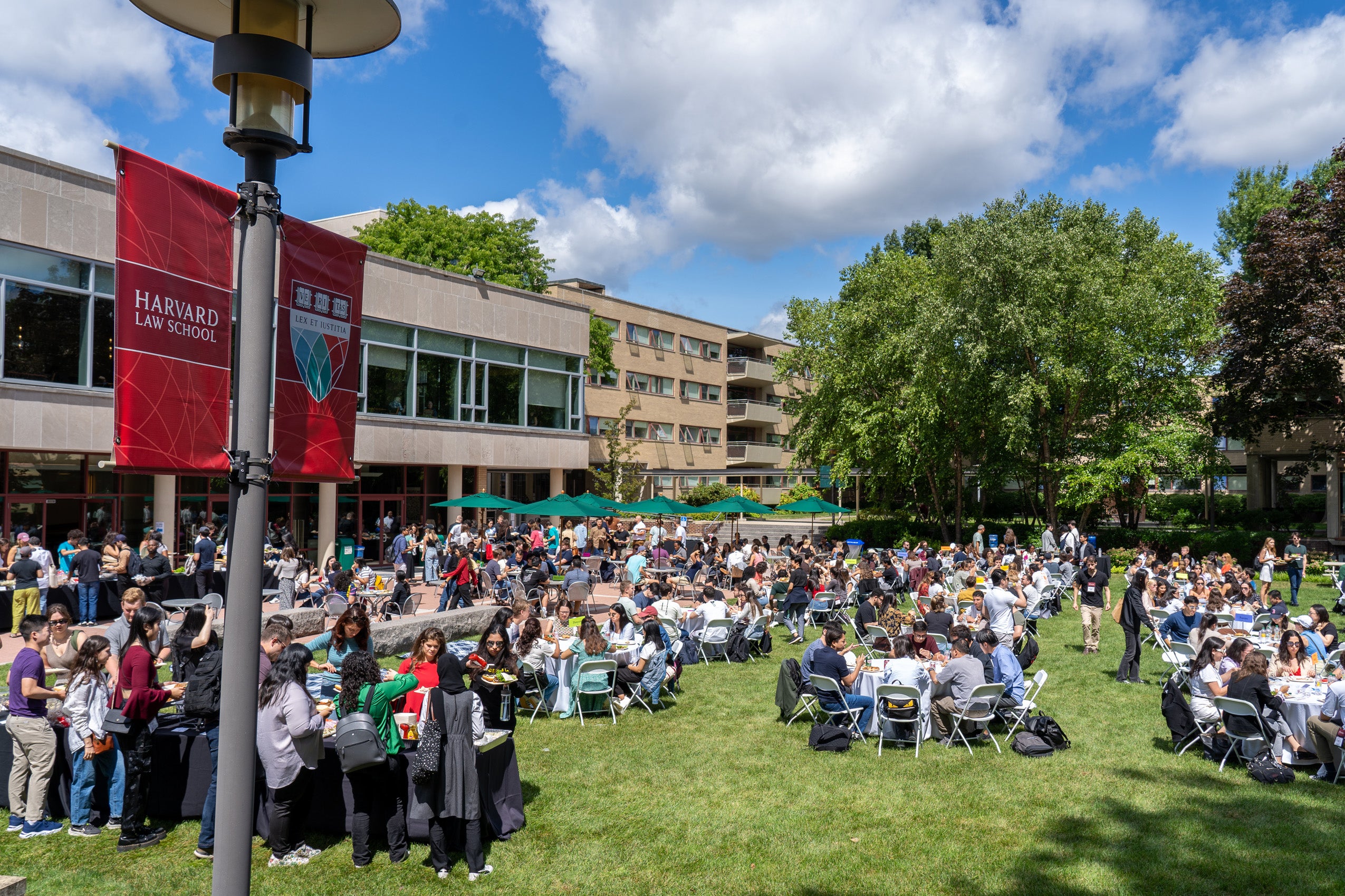 A view of a field with gathering of students at tables on campus