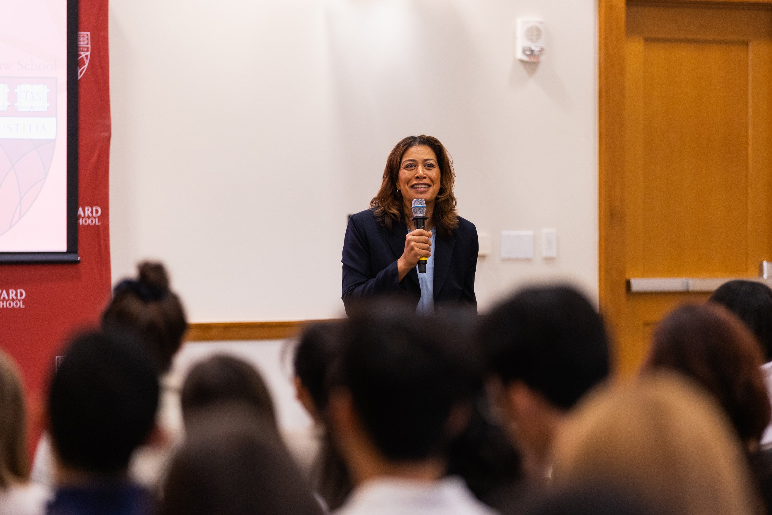A woman with a microphone speaks to an audience during an orientation day zero event.