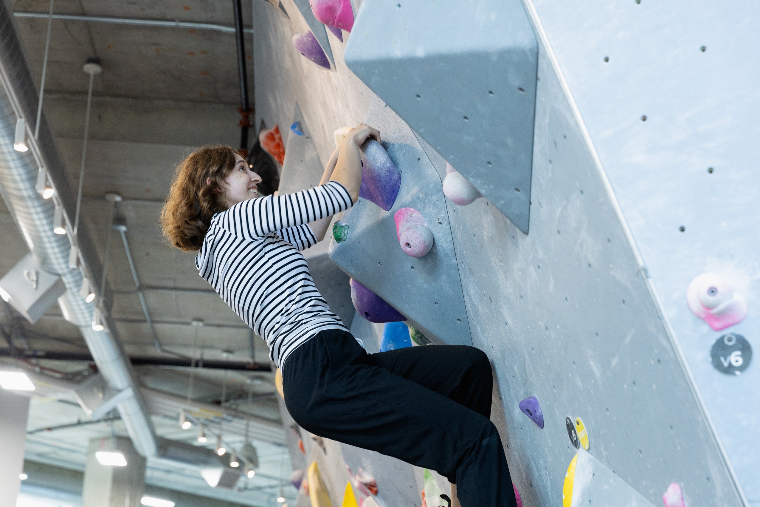 A student rock climbing at a climbing gym.