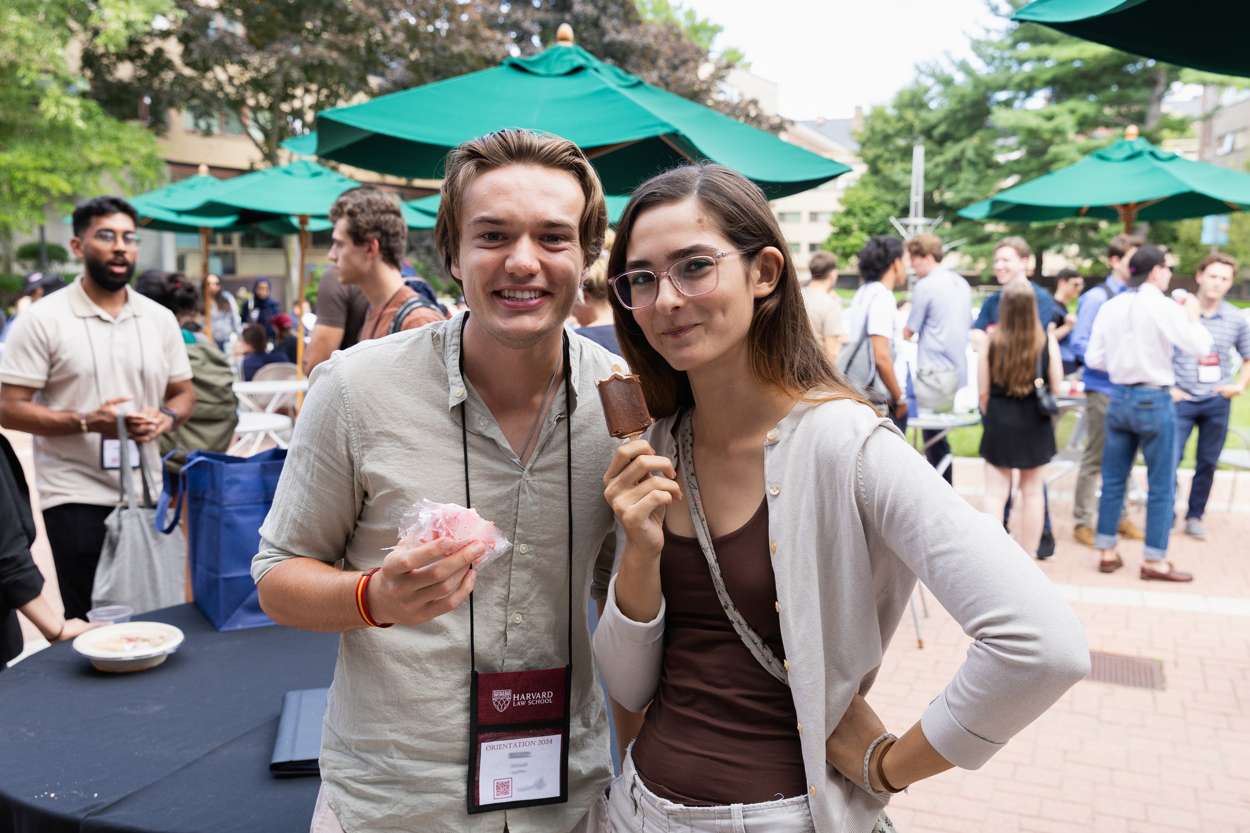 A man and a women pose for the camera holding ice creme treats at an outside event during orientation.