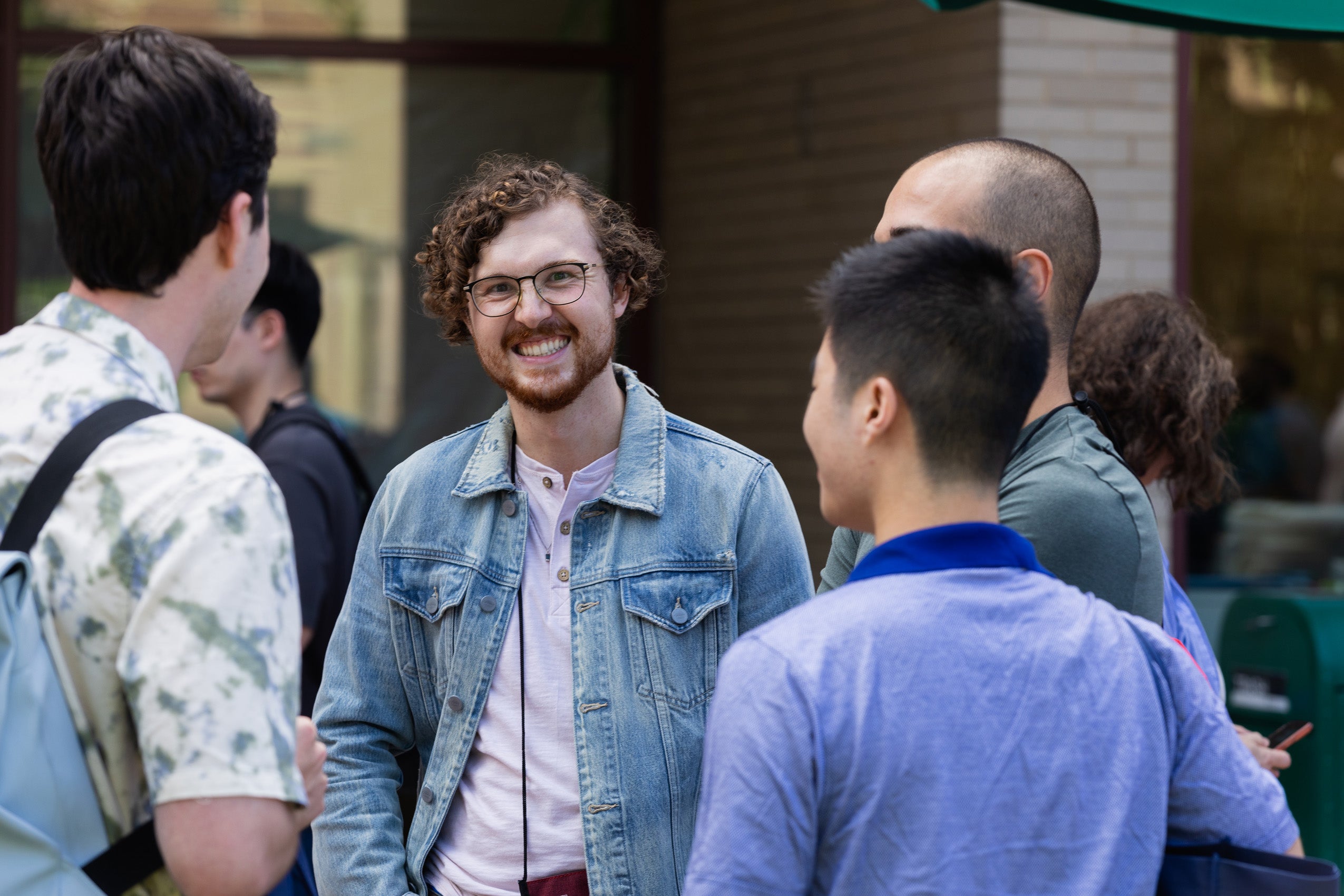 A man smiles as he with others at an outside event during orientation.