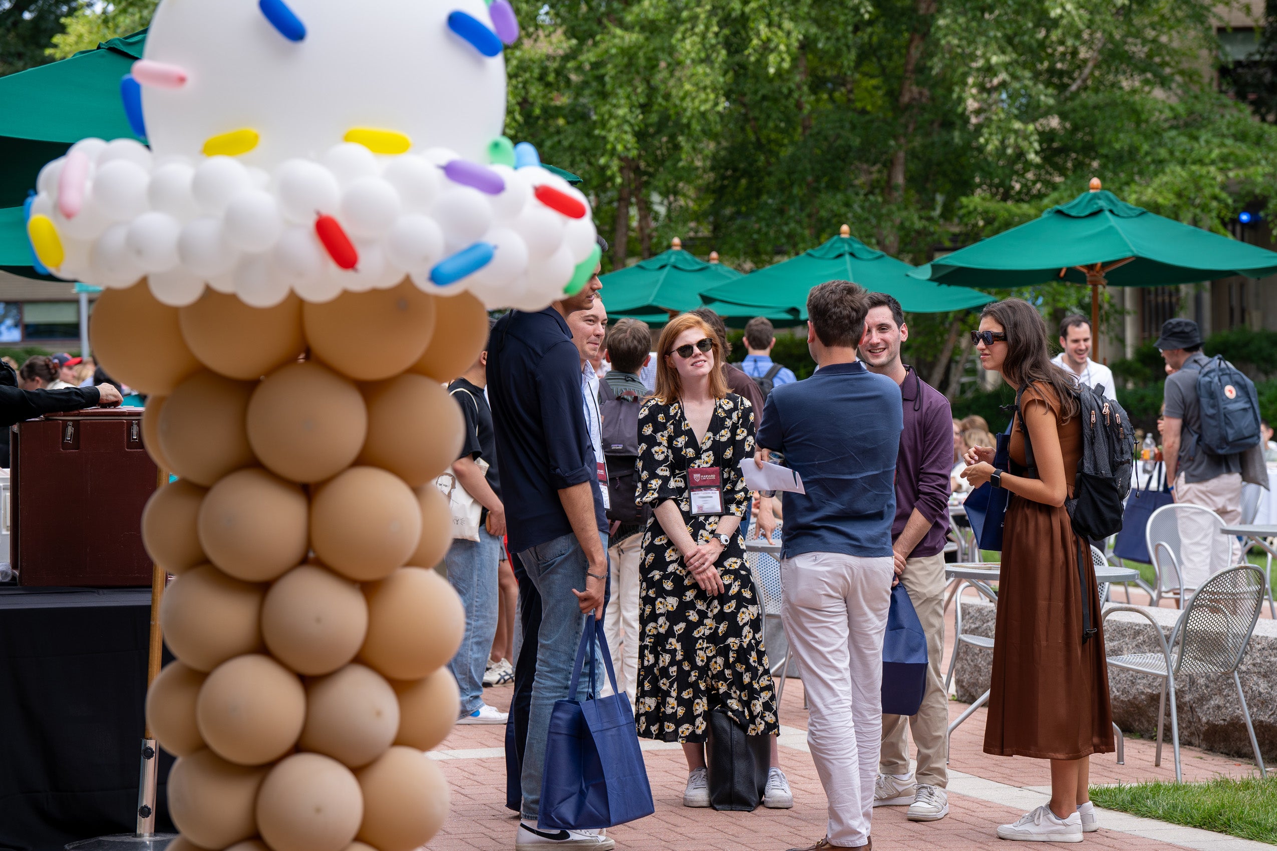 A large ice creme cone made of balloons decorates an outside event with many students